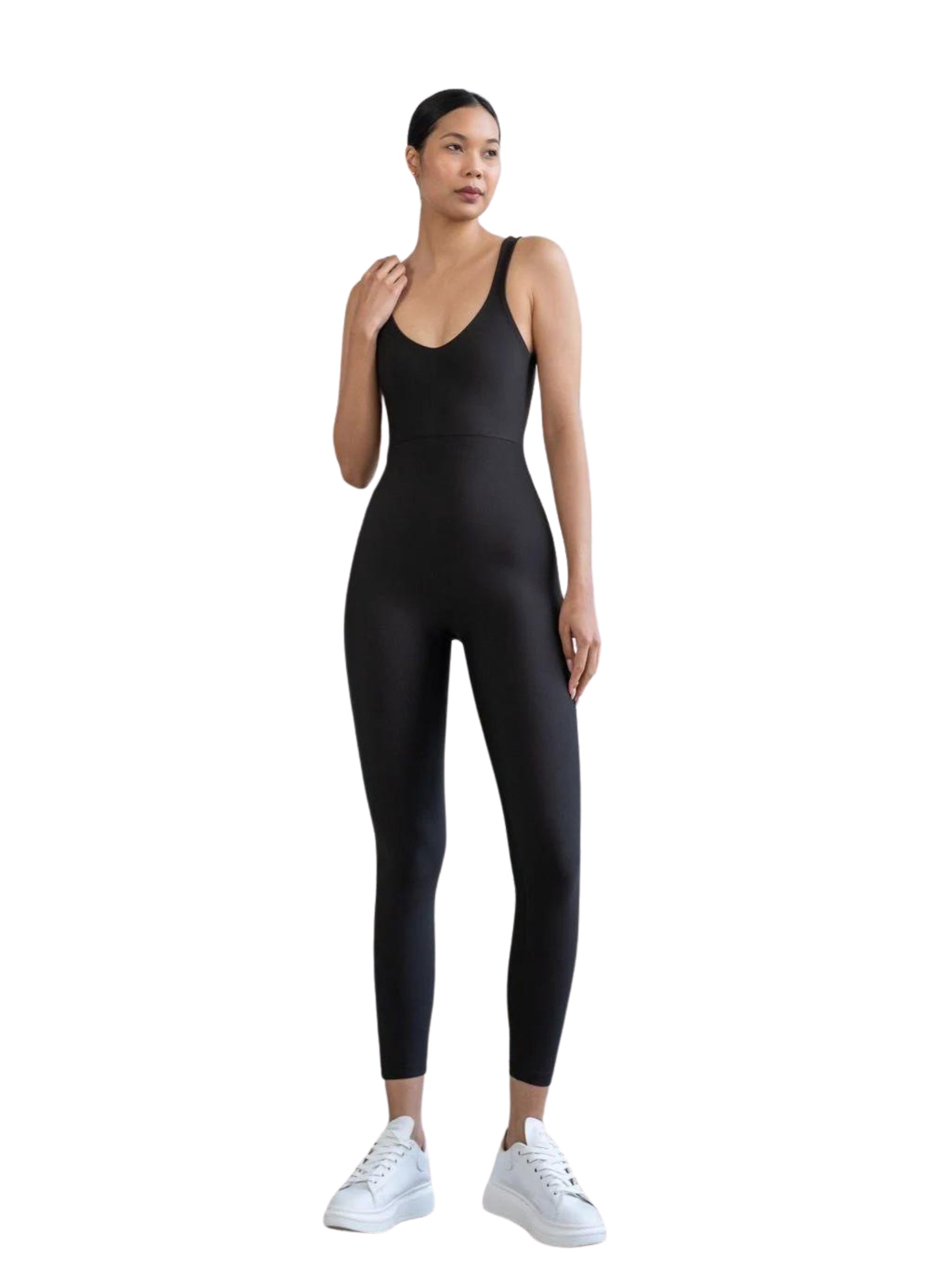 Person in einem Lismina 1600-Ganzkörper-Jumpsuit und weißen Turnschuhen, die vor einem schlichten weißen Hintergrund steht.
